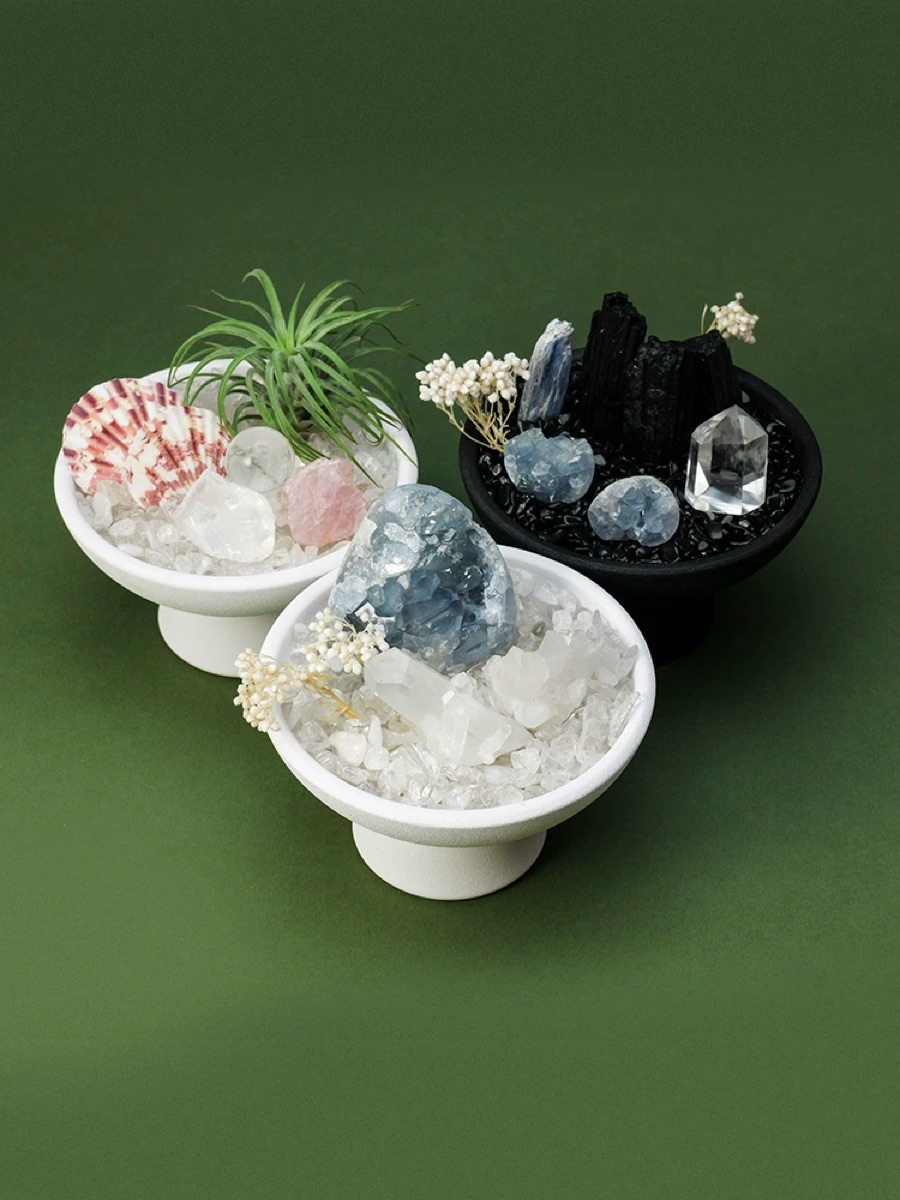 Three crystal grid compositions pairing natural stones, plants and contrasting vessels